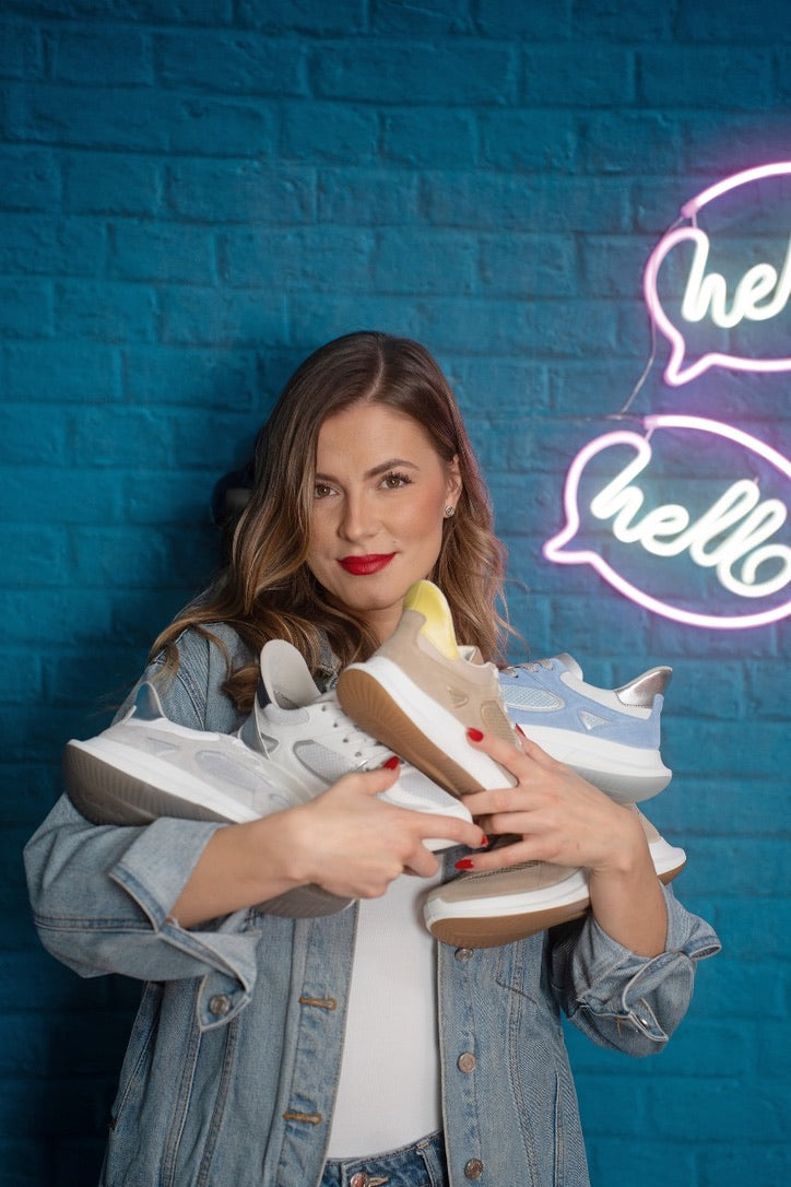 A woman hugging an armful of ara sneakers