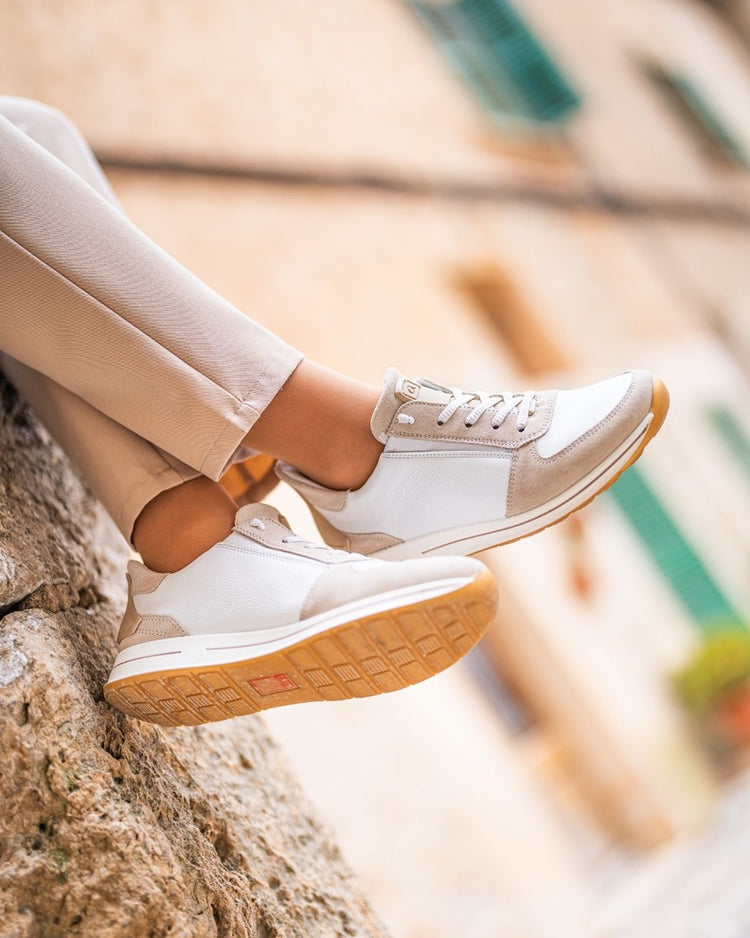 ara sneakers resting on a sunlit stone wall